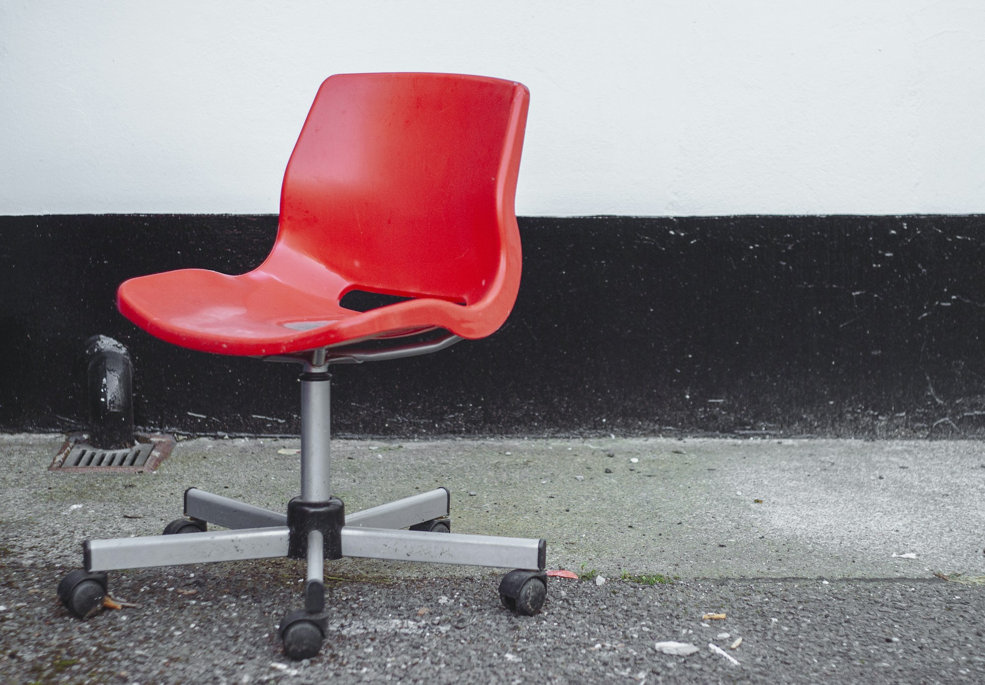 A usable red office chair left out on a sidewalk